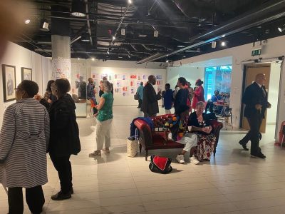 Lots of people in an art gallery, talking and looking at the art