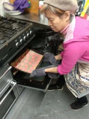 Image of woman squatting down to put a tray of cookies into an over.